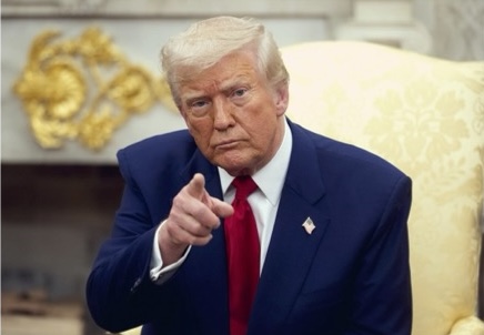 A photo of Donald Trump wearing a navy suit and red tie. He is pointing at the camera and wearing a flag pin.
