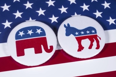 Photo of two buttons featuring an elephant and donkey, covered in American flag color on top of an American flag